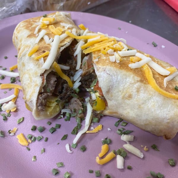 Phat Daddy's BBQ burrito, cut open to show meat, cheese, and vegetables, on a purple plate.