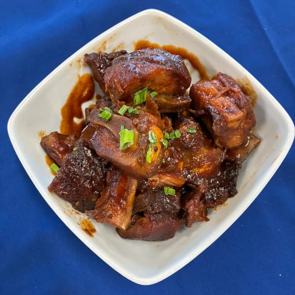 Phat Daddy's BBQ ribs, glistening with sauce and garnished with green onions in a white bowl.