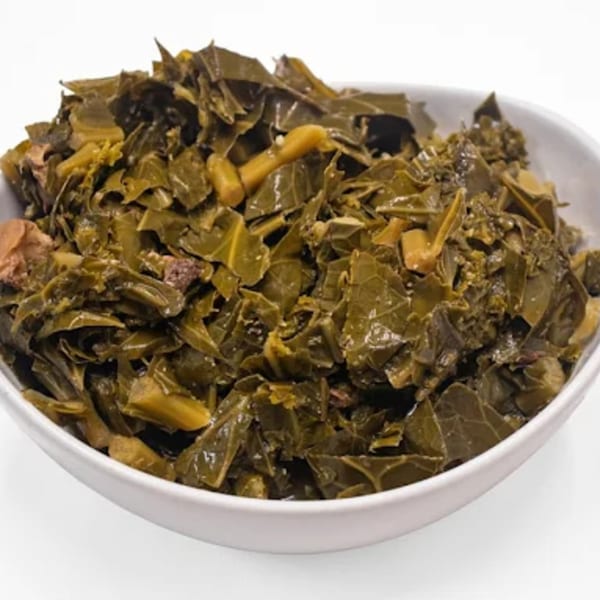 A white bowl filled with Phat Daddy's collard greens, featuring dark green leaves and some meat.