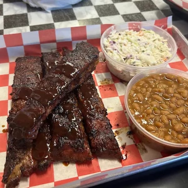 Phat Daddy's BBQ ribs with sauce, coleslaw, and baked beans on a checkered paper-lined tray.